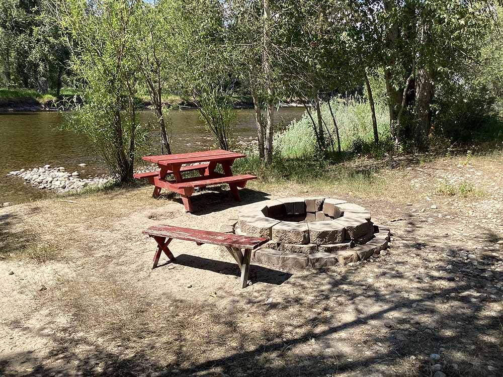 A fire pit and picnic table next to the river at BLACK RABBIT RV PARK