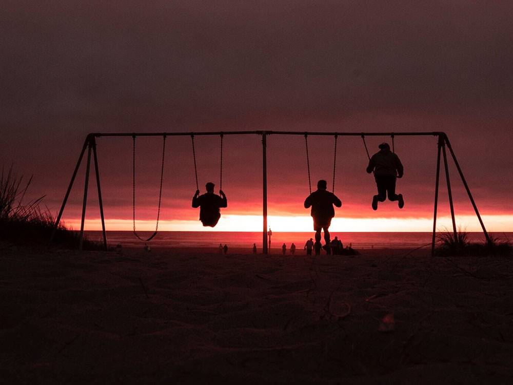 Kids on swing set against dusk sky at CIRCLE CREEK RV RESORT