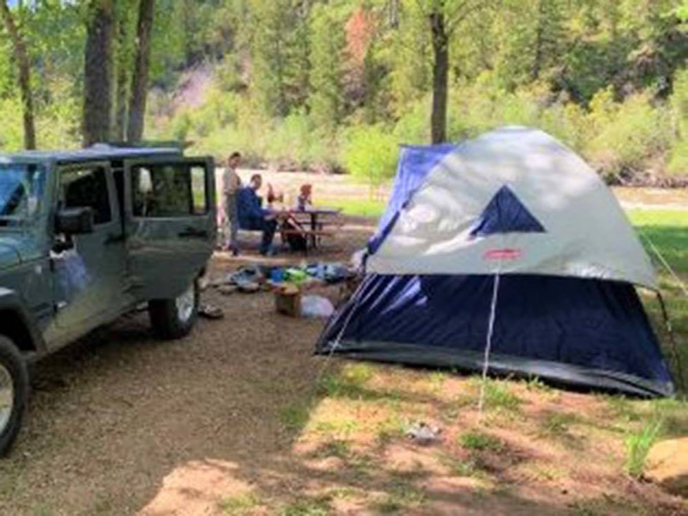 Jeep and tent in dirt site at DOLORES RIVER RV RESORT BY RJOURNEY
