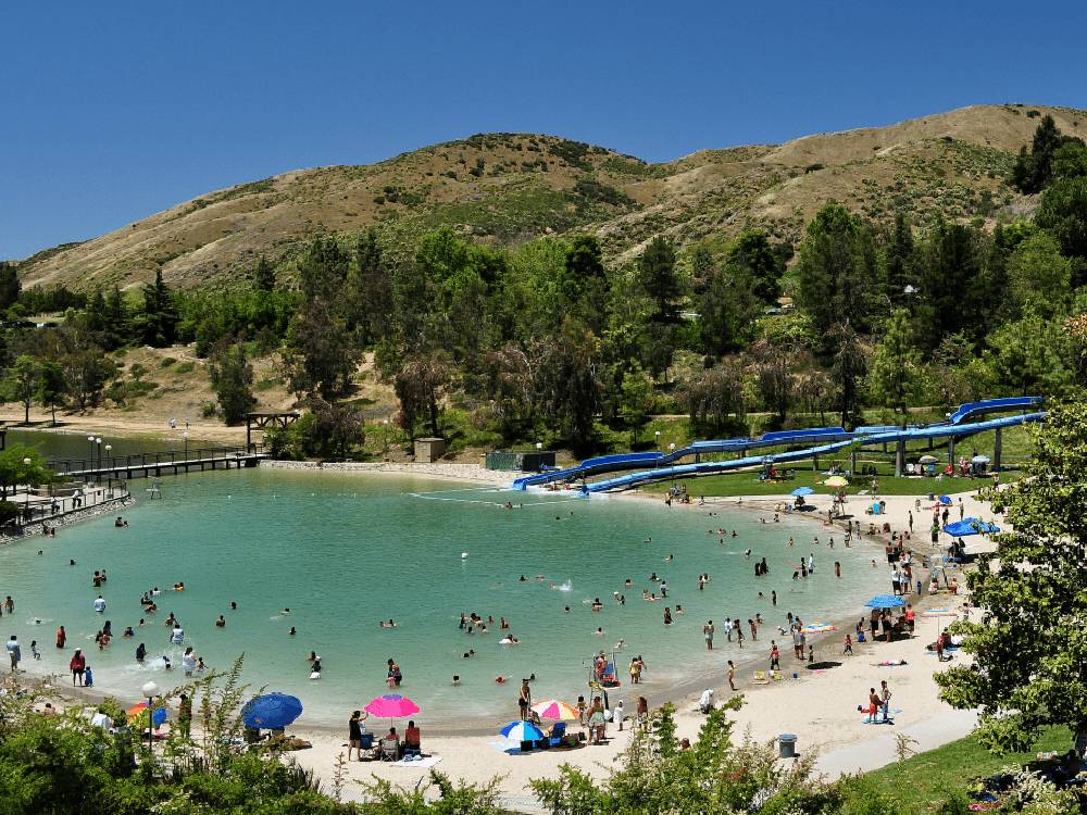 Large swimming pool with slides and people in the lake