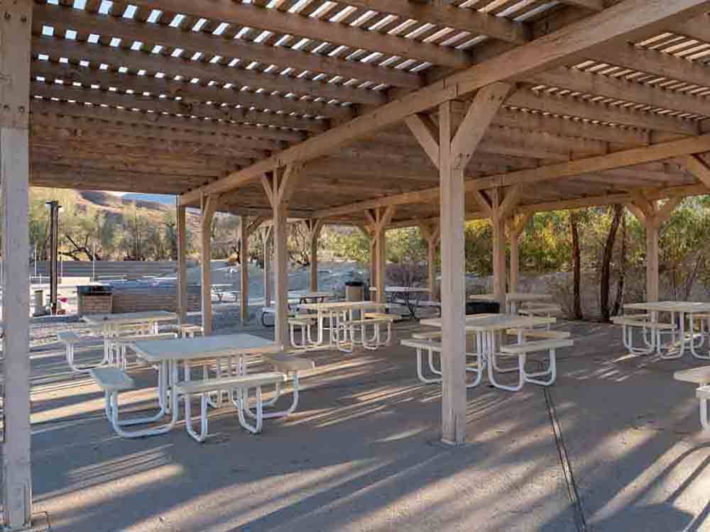 A group of tables under a large pergola at PALM CANYON HOTEL AND RV RESORT
