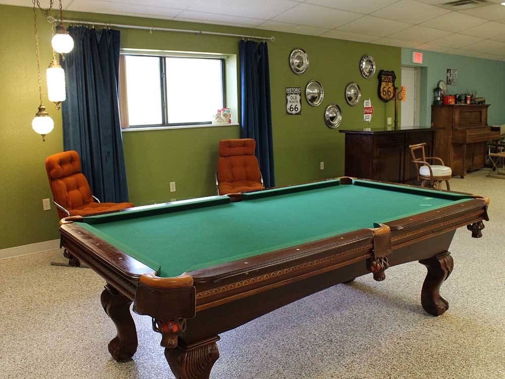 A pool table with orange colored chairs in background at ELK CREEK RV PARK