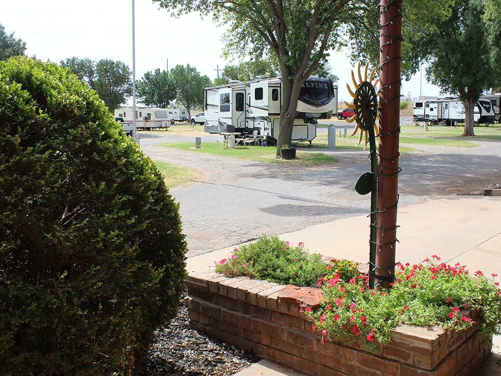 A view of RVs in sites with raised flower bed in foreground at ELK CREEK RV PARK
