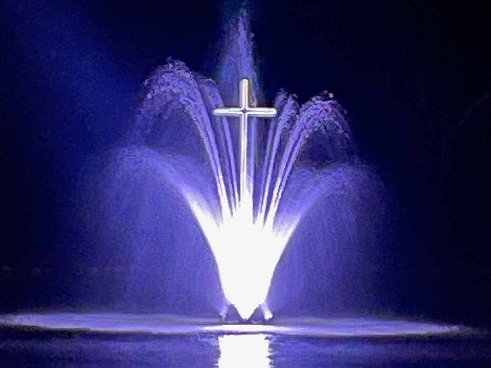The fountain with a cross lit up a night at LEISURE ACRES CAMPGROUND