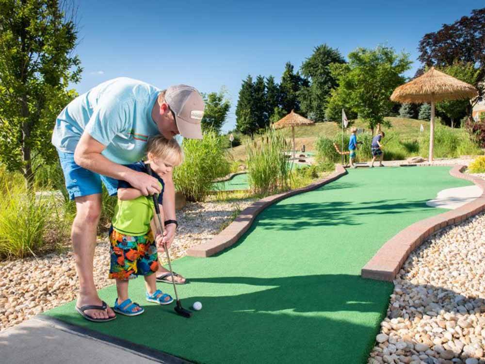 A man and small child playing mini golf at CHERRY HILL PARK