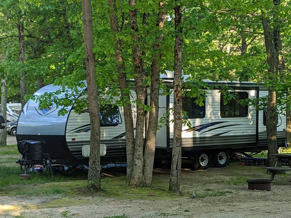 A travel trailer under trees at INDIAN ROCK RV PARK