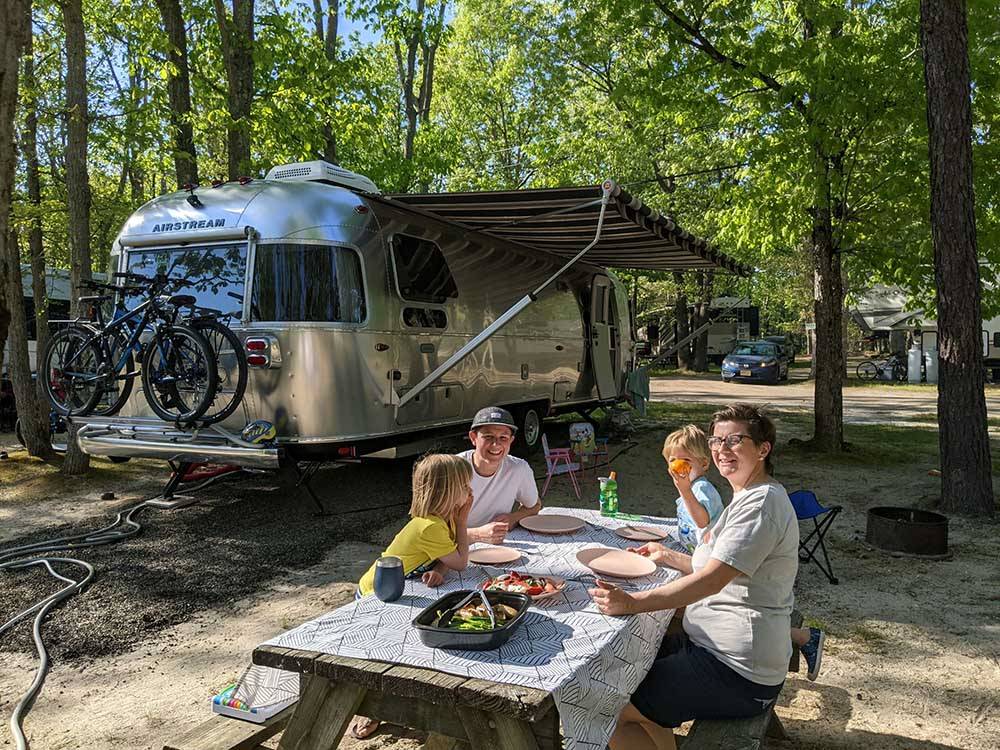 A family eating outside of their trailer at INDIAN ROCK RV PARK