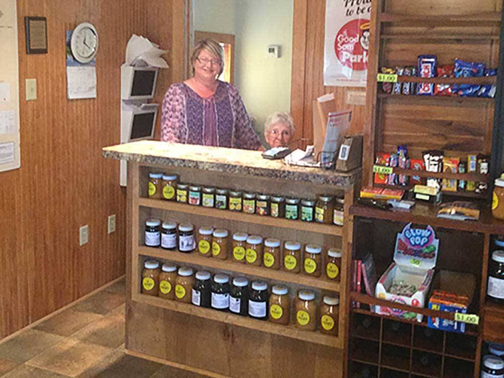 Two staff workers behind a shelf full of jars of honey at PECAN GROVE RV PARK