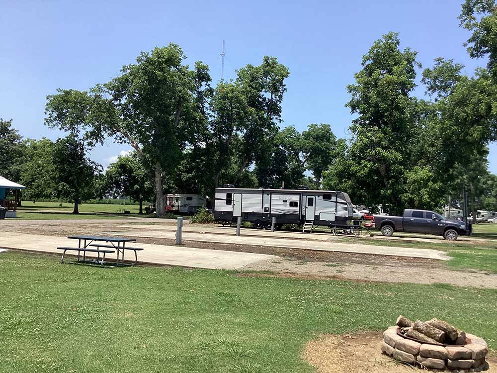 A travel trailer parked next to some empty sites at PECAN GROVE RV PARK