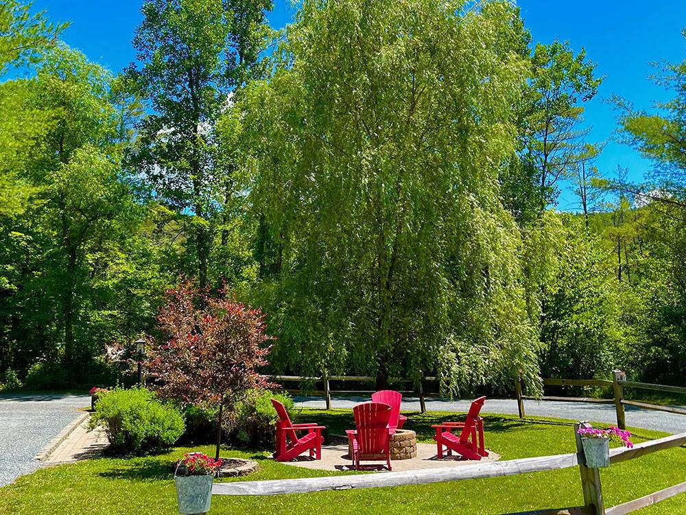 A community fire ring and red Adirondack chairs