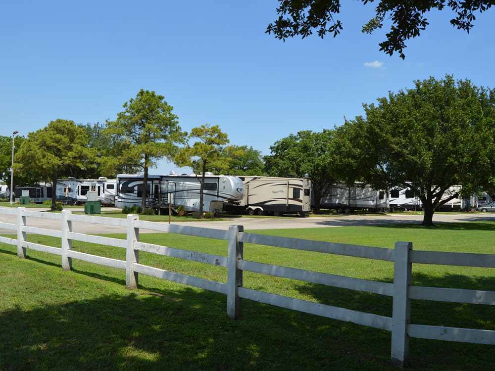 A white fence in front of RV sites at TRADERS VILLAGE RV PARK