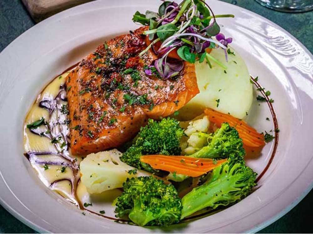A dinner plate with cooked salmon and vegetables at RIVER'S EDGE RV PARK & CAMPGROUND