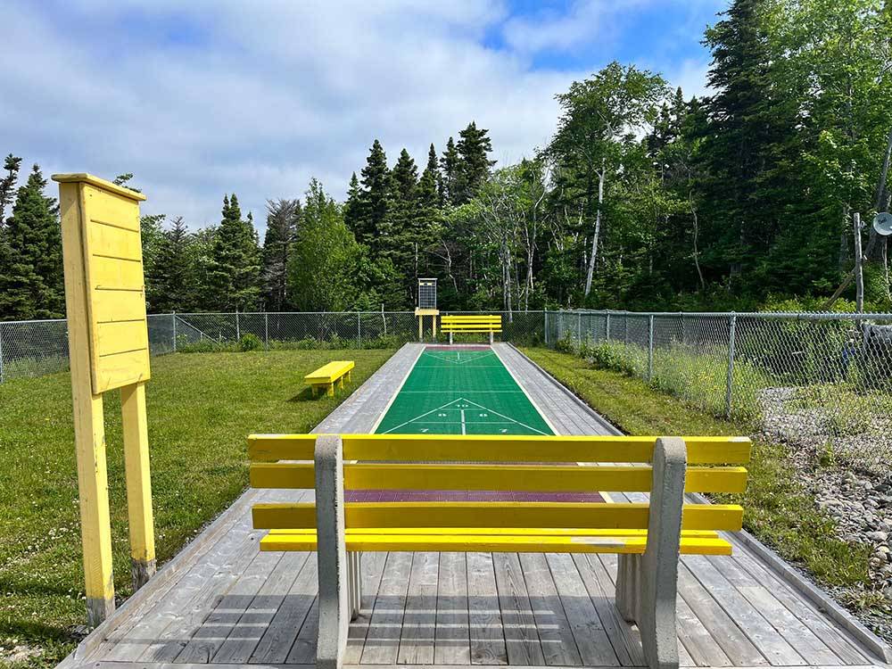 The shuffleboard court with yellow seats at HAROLD W. DUFFETT SHRINERS RV PARK