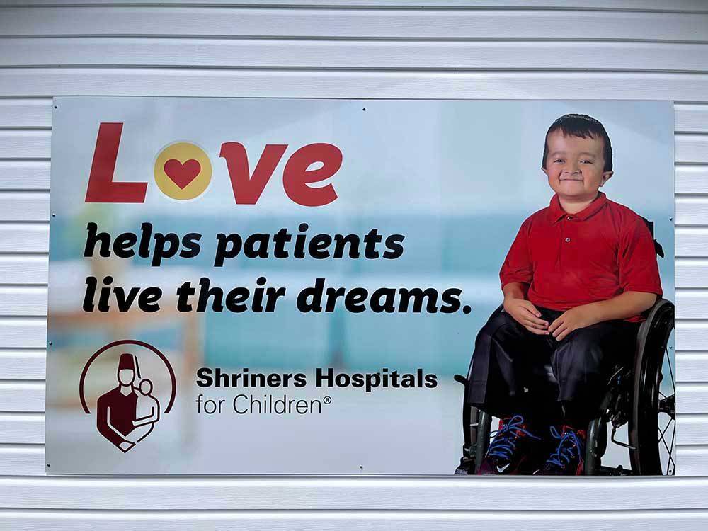  A banner of a child in a wheelchair at HAROLD W. DUFFETT SHRINERS RV PARK
