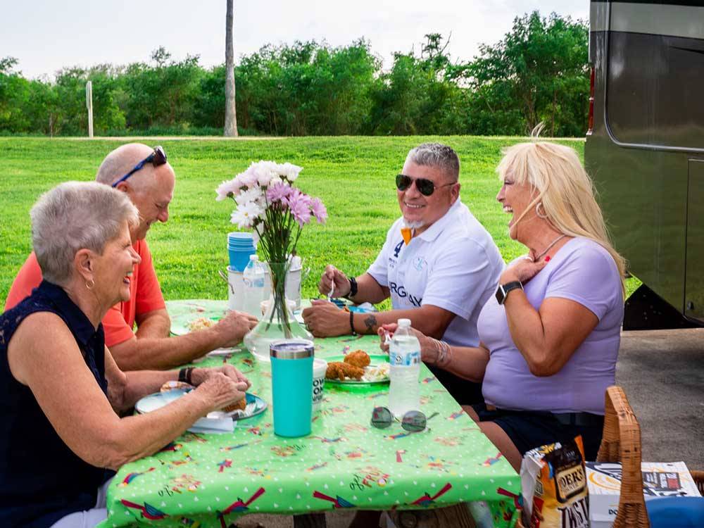 Two couples enjoying dinner next to their RV at RIVER BEND RESORT & GOLF CLUB