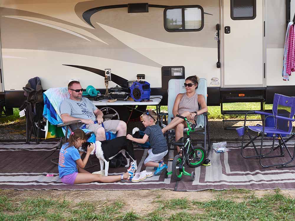Family and dog sitting next to their RV at JELLYSTONE PARK AT MAMMOTH CAVE