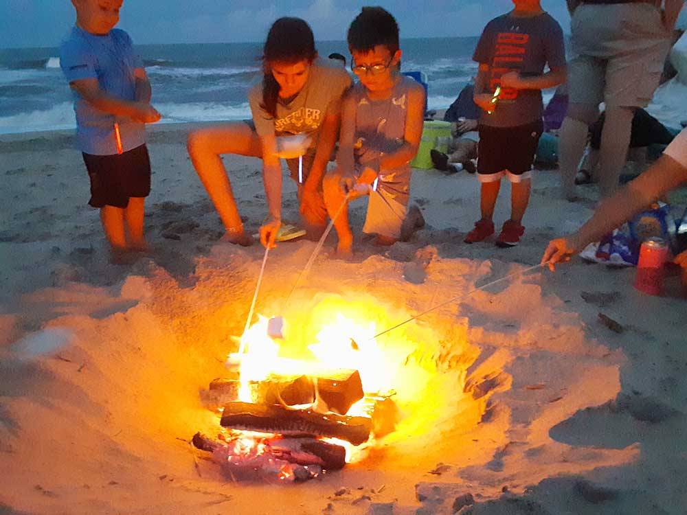 Kids roasting marshmallows on the beach at CAMP HATTERAS RV RESORT & CAMPGROUND