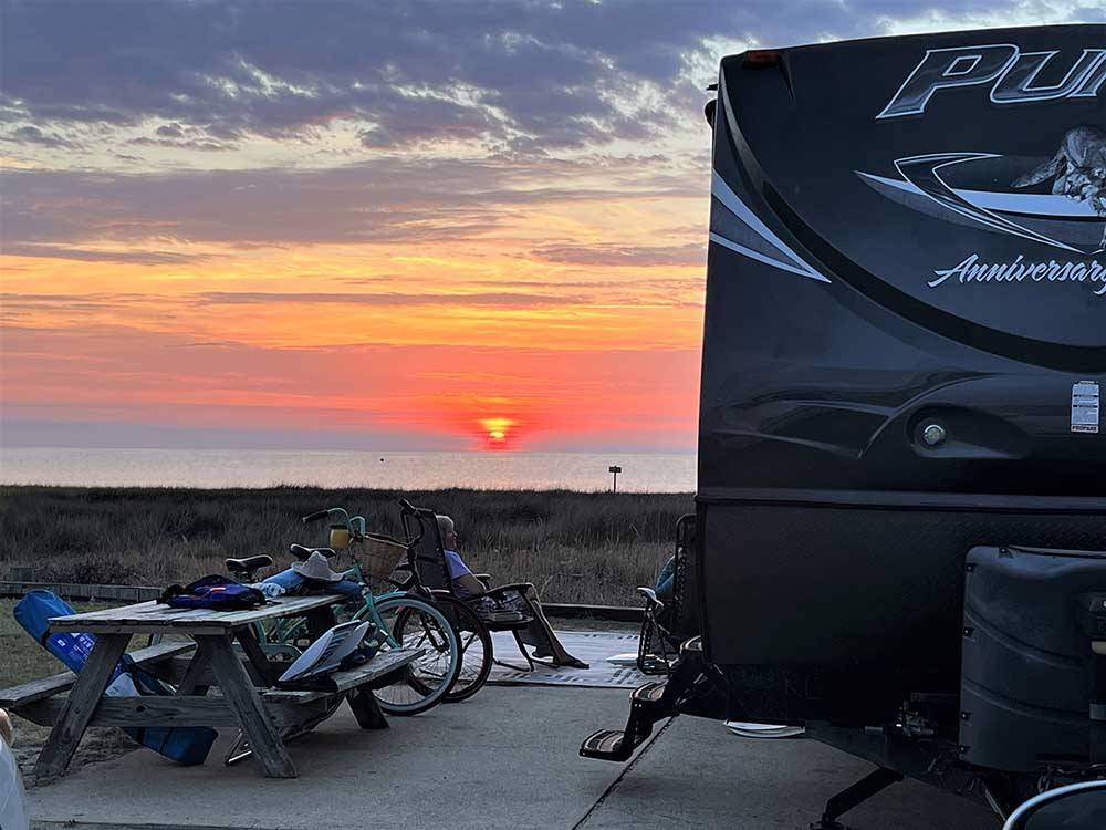 A motorhome parked in a paved site at CAMP HATTERAS RV RESORT & CAMPGROUND