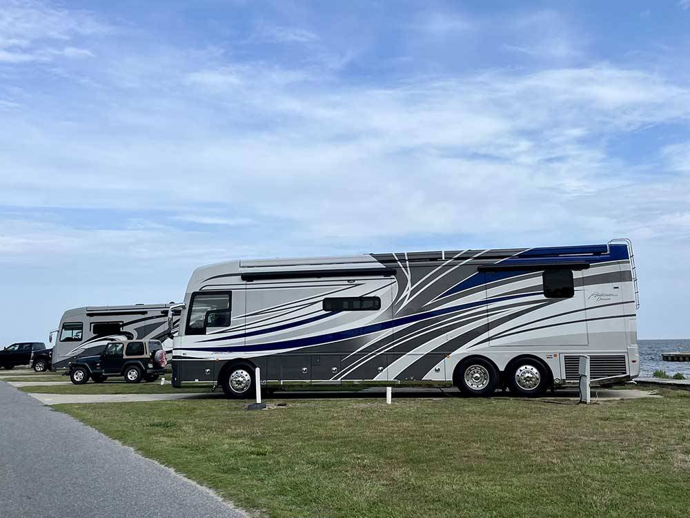 A row of motorhomes parked in sites at CAMP HATTERAS RV RESORT & CAMPGROUND