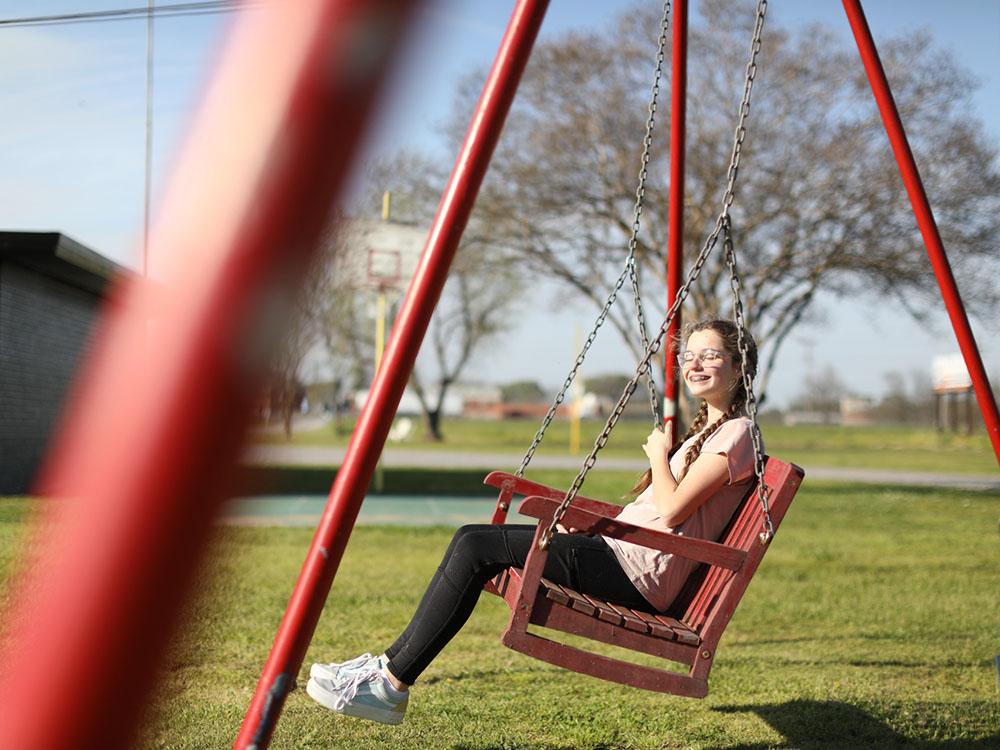 A woman on a bench swing at THE OUACHITA RV PARK