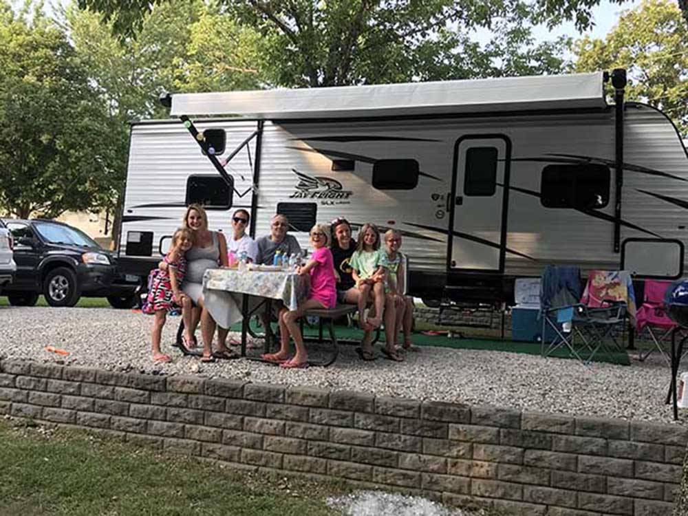 A family sitting outside of a trailer at LAZY DAY CAMPGROUND