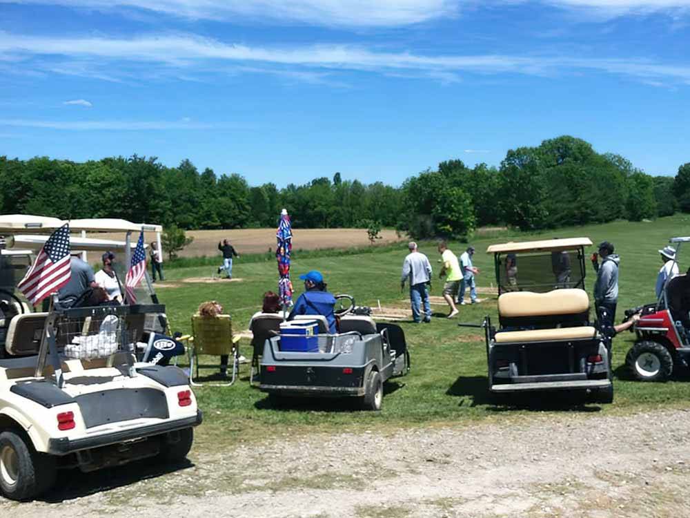 A group of golf carts and people playing horseshoes at TOWN & COUNTRY CAMP RESORT