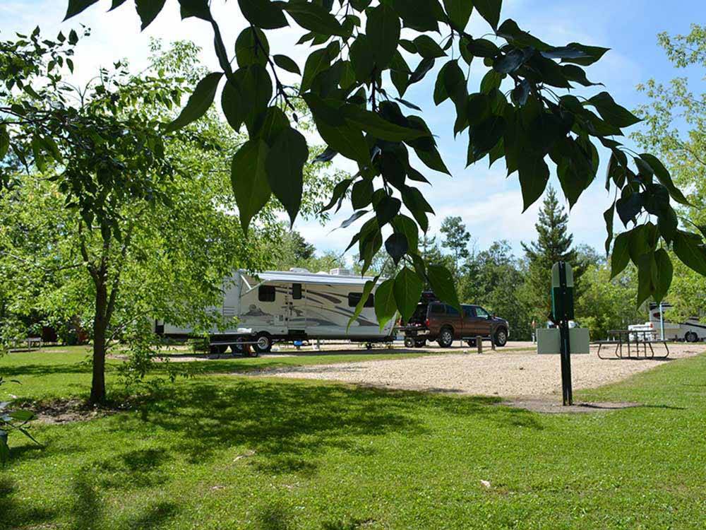 Looking at some of the gravel RV sites thru trees at SHERK'S RV PARK