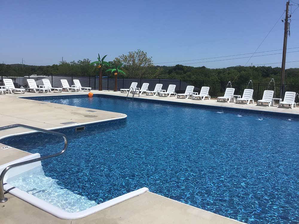 The fenced in swimming pool with lounge chairs at OWL CREEK MARKET + RV PARK