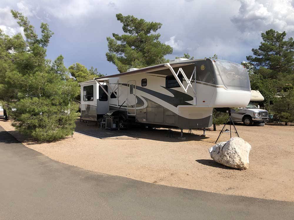 Fifth wheel parked between trees in campsite at ZUNI VILLAGE RV PARK