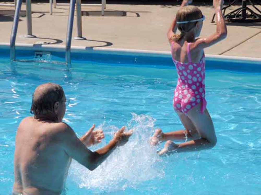 A man throwing a child in the swimming pool at AMERICA'S BEST CAMPGROUND