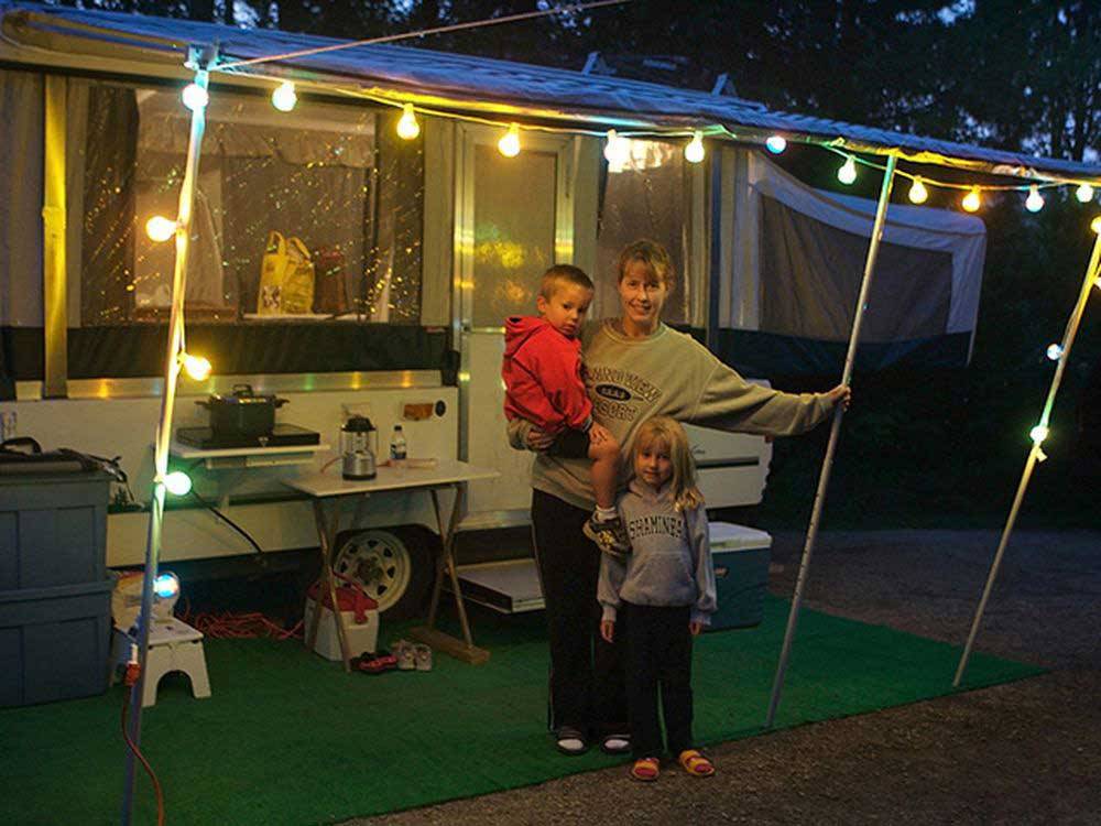 Mother and children outside trailer at night at LAKE BYLLESBY CAMPGROUND