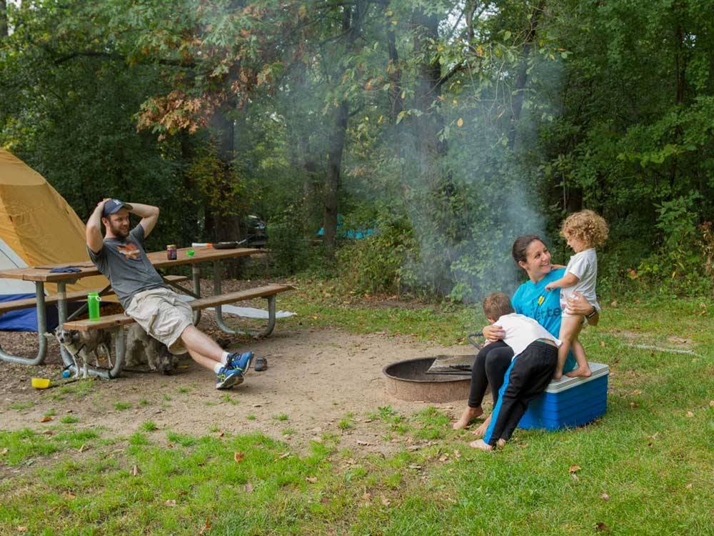 Family relaxing by fire pit at campsite at LAKE BYLLESBY CAMPGROUND