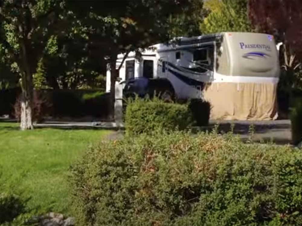 A fifth wheel trailer next to grass at VICTORIAN RV PARK