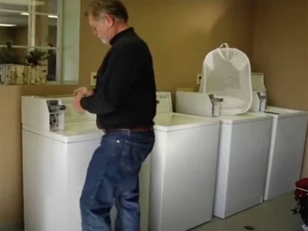 A man using one of the washing machines at VICTORIAN RV PARK