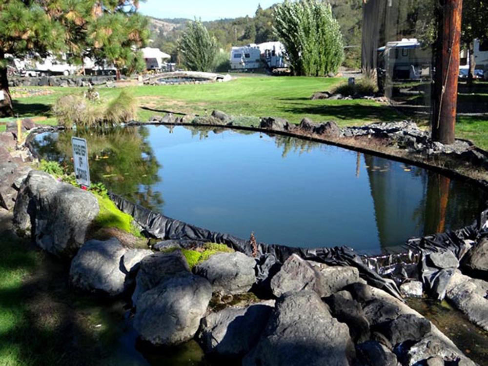 Landscape with small pond and RVs in background at ON THE RIVER GOLF & RV RESORT