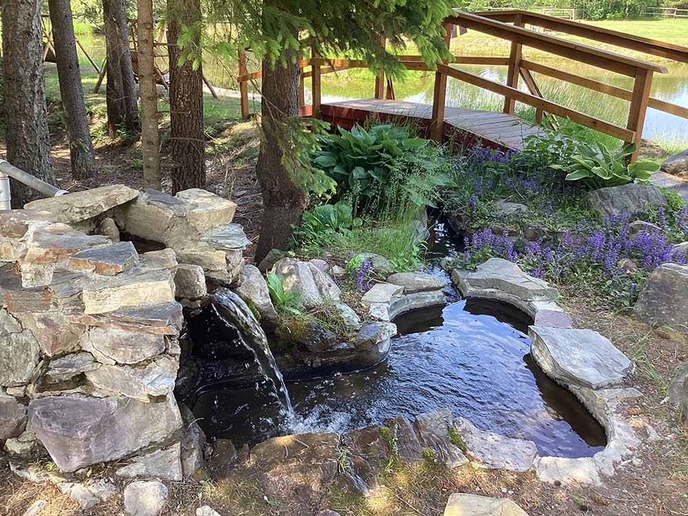 A small waterfall by a wooden bridge at MOUNTAIN MEADOW RV PARK & CABINS