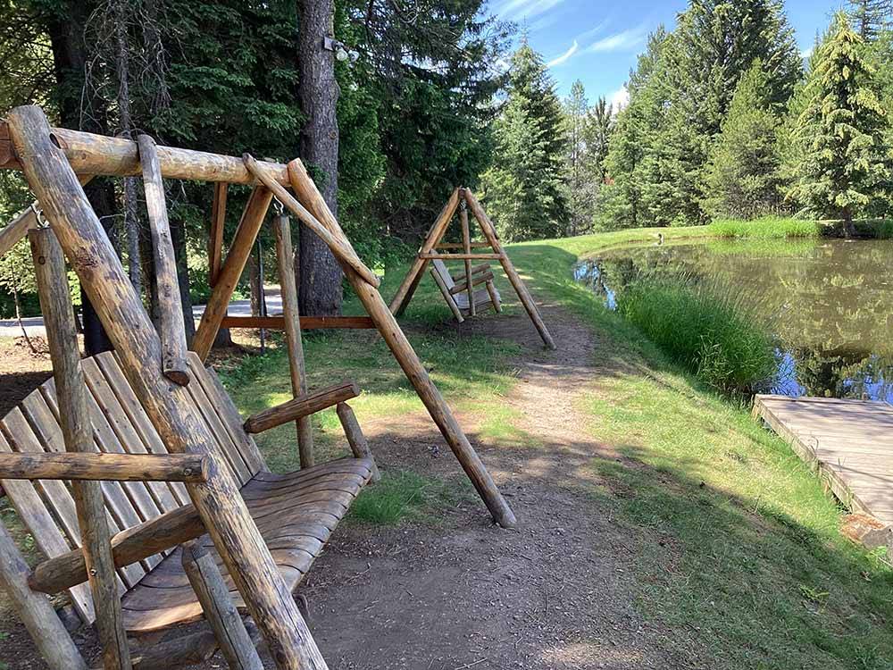 A couple of swinging benches by the water at MOUNTAIN MEADOW RV PARK & CABINS
