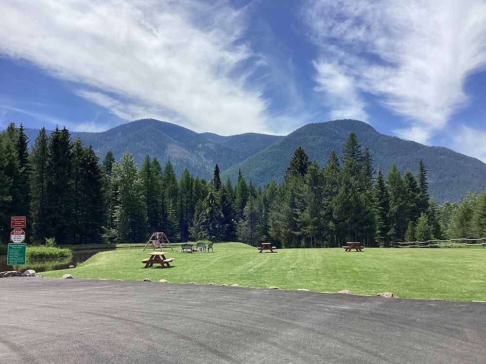 A group of picnic tables in a grassy field at MOUNTAIN MEADOW RV PARK & CABINS