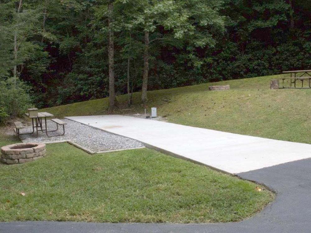 A concrete RV site with a bench and fire pit at CREEKWOOD RESORT