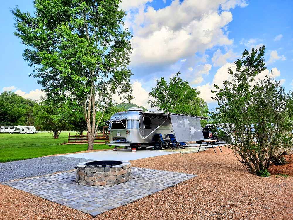 An Airstream in a paved RV site with a fire pit at BIG MEADOW FAMILY CAMPGROUND