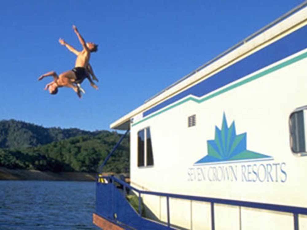 Kids jumping off of a boat into the water at MOUNTAIN GATE RV PARK