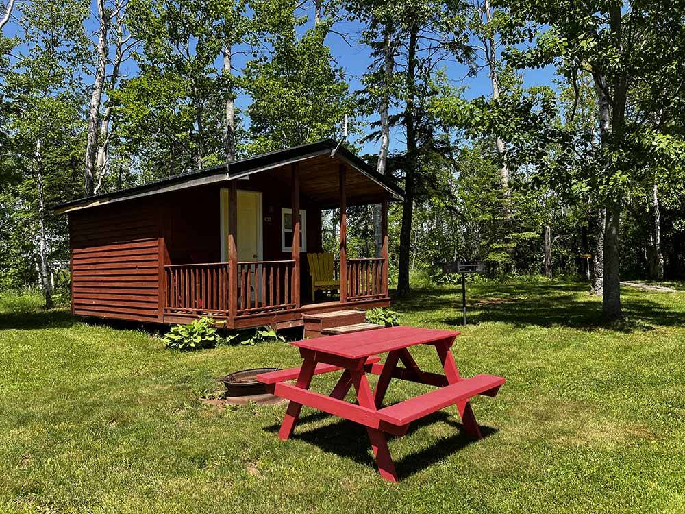 A red picnic table in front of a rental cabin at BORDEN/SUMMERSIDE KOA