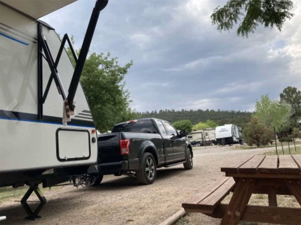 Travel trailer and pickup truck in site with picnic table at TURQUOISE TRAIL CAMPGROUND & RV PARK