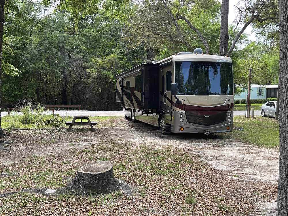 A motorhome in a sandy RV site at RIVERS EDGE RV CAMPGROUND