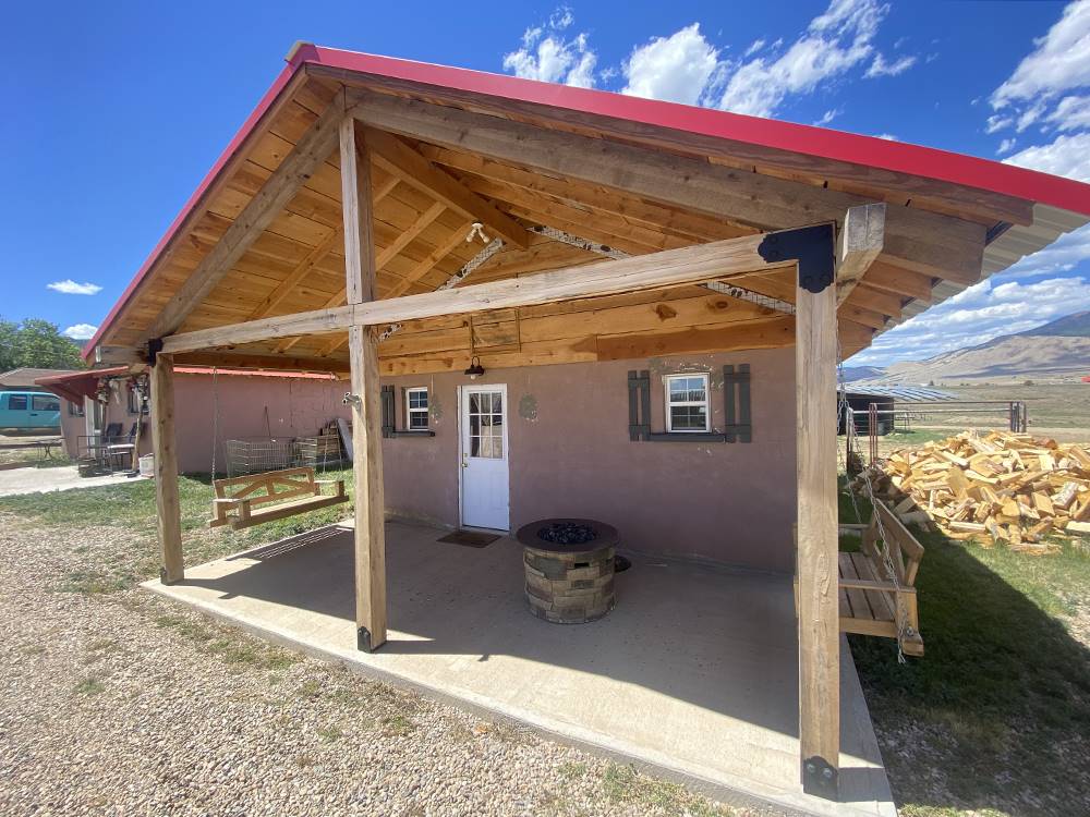 Porch swings on a covered porch with a fire pit