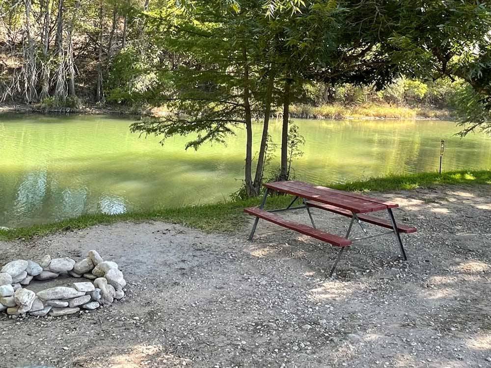 A picnic table by the river at BY THE RIVER RV PARK & CAMPGROUND