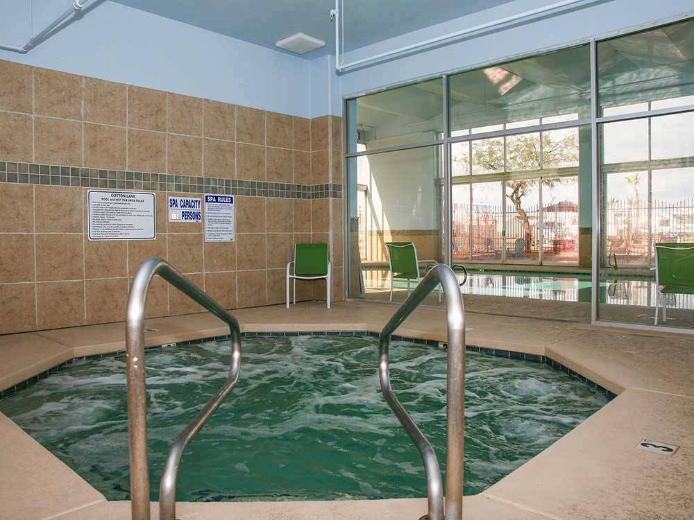 Indoor hot tub with green chairs nearby at COTTON LANE RV RESORT