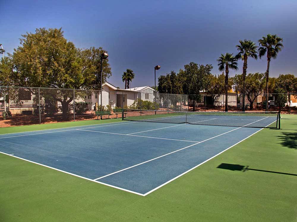 Tennis court with palm trees and blue sky in background at SUNRISE RV RESORT