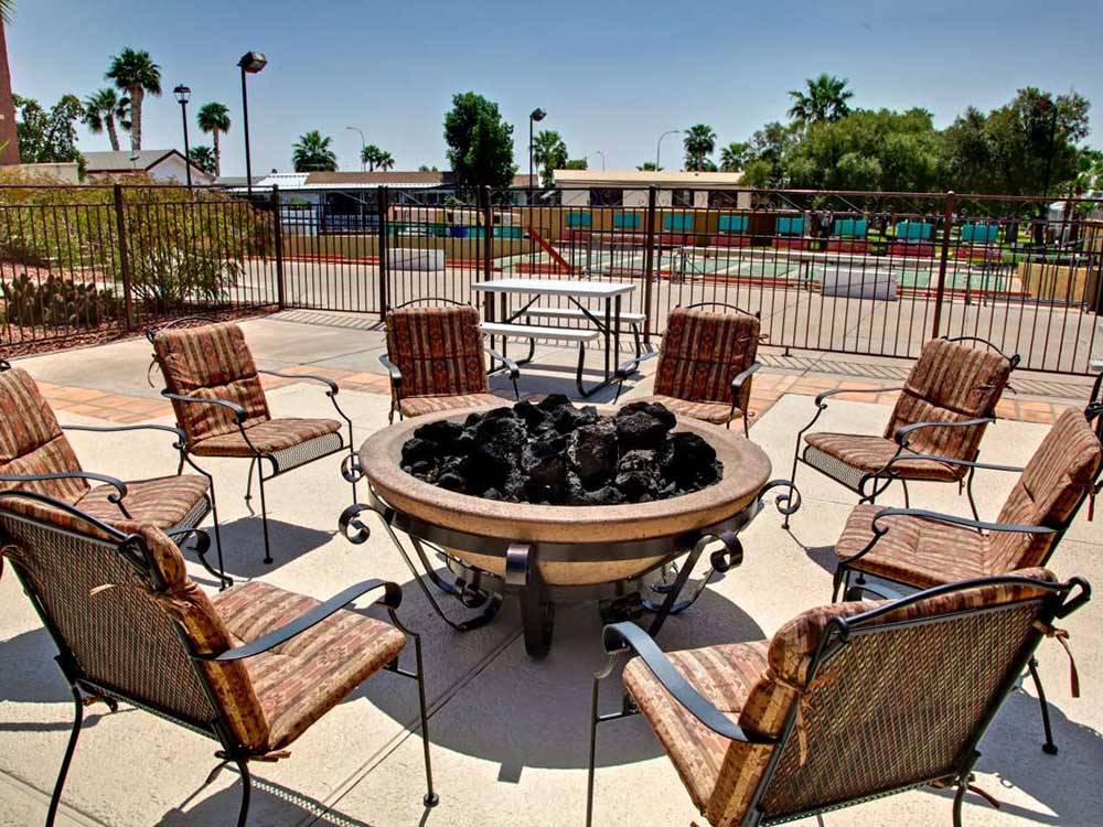 Chairs with cushions and wrought-iron frames assemble around a fire pit at SUNRISE RV RESORT