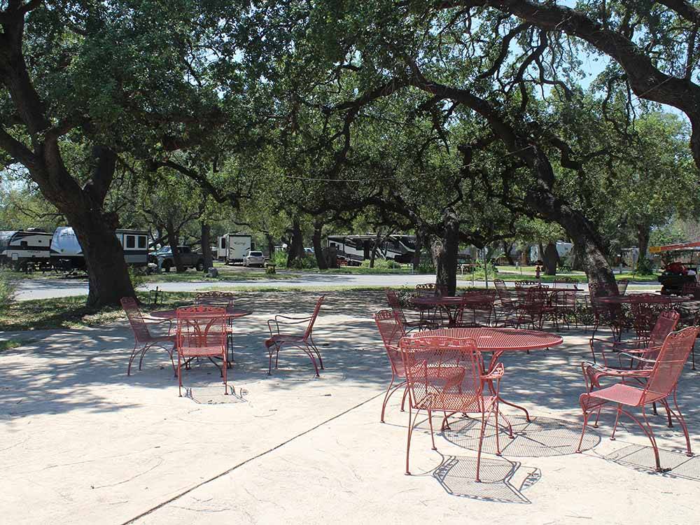 Red chairs and tables under trees at QUAIL SPRINGS RV PARK